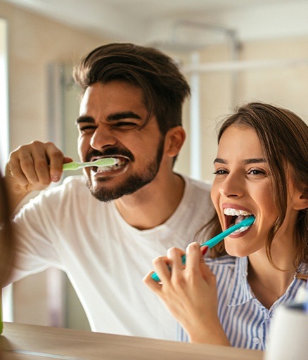 Man and woman brushing teeth together