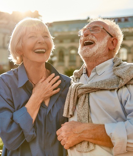 Man and woman laughing together enjoying the benefits of all on four dental implants