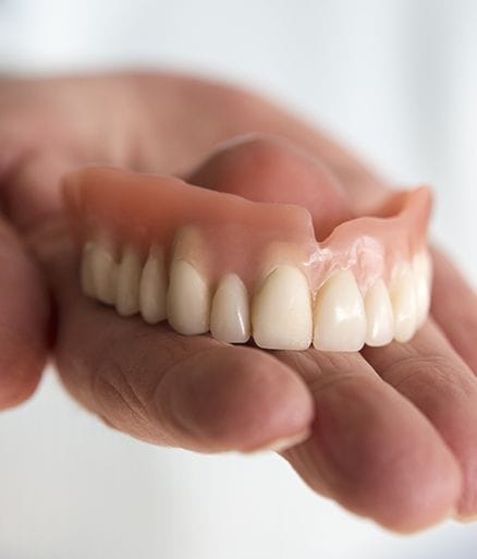 Hand holding full denture
