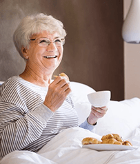 a woman with dentures eating breakfast in bed