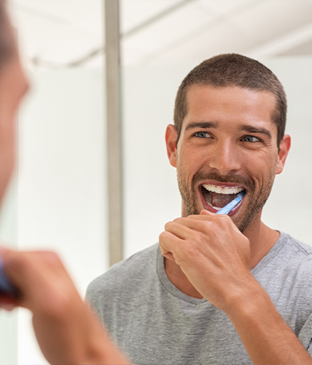 Man brushing teeth to maintain tooth colored filling