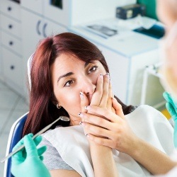 Woman in need of sedation dentistry covering her smile