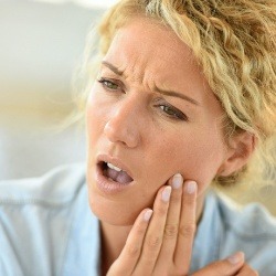 Woman in need of emergency dentistry holding cheek in pain