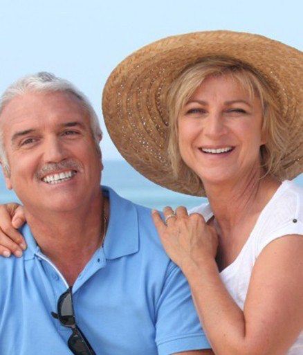 Man and woman smiling after dental implant supported denture placement