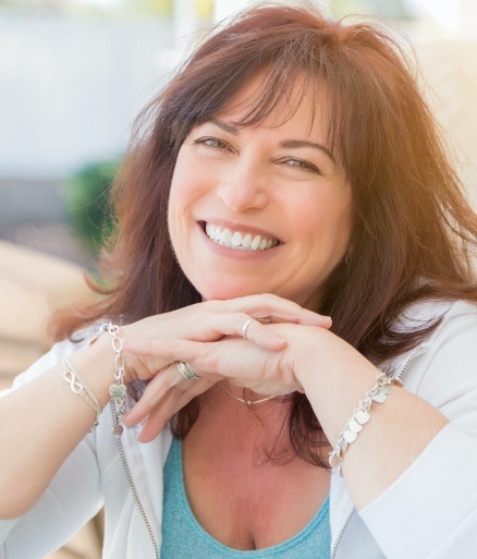 Woman sharing healthy smile due to maintaining and caring for dental implants