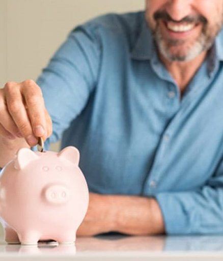Man placing coins in a piggy bank to budget for the cost of Invisalign