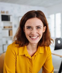 Woman in yellow shirt smiling while working in office