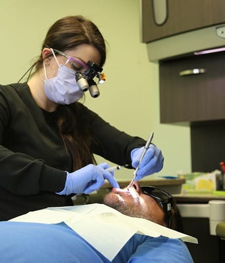 Dental team member assessing smile for symptoms of gum disease