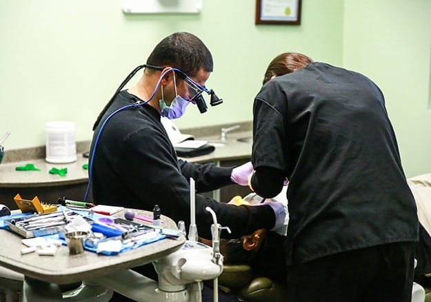 Dentist and dental team member treating patient under sedation dentistry