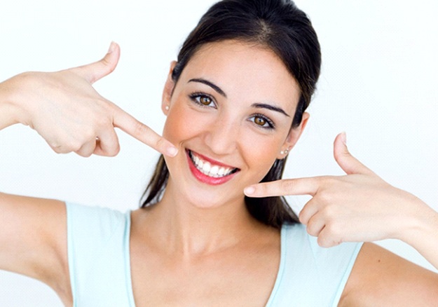 woman with veneers in Glenpool pointing to her smile