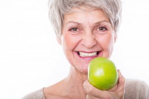woman smiling holding green apple