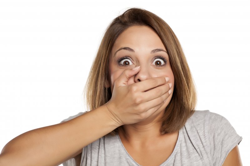 young woman with hand over mouth in shock