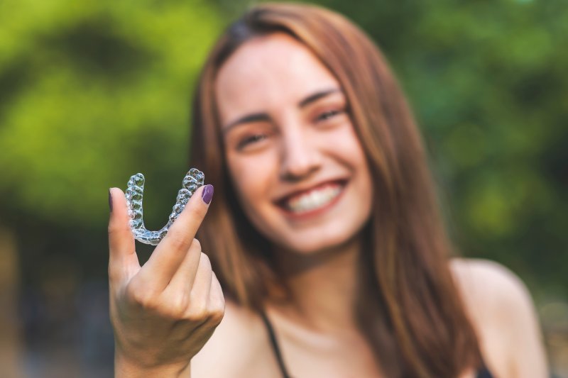 Young woman holding her Invisalign aligner.